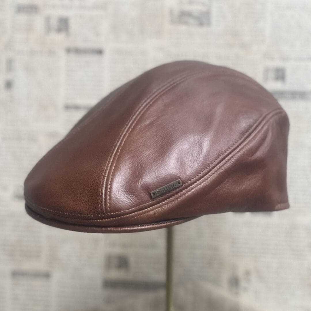 A brown leather hat on top of a stand.