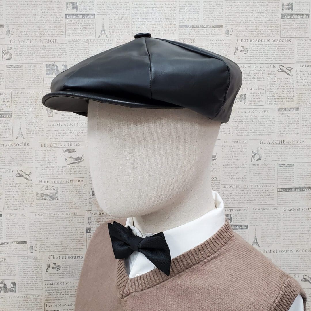 A mannequin wearing a black hat and bow tie.