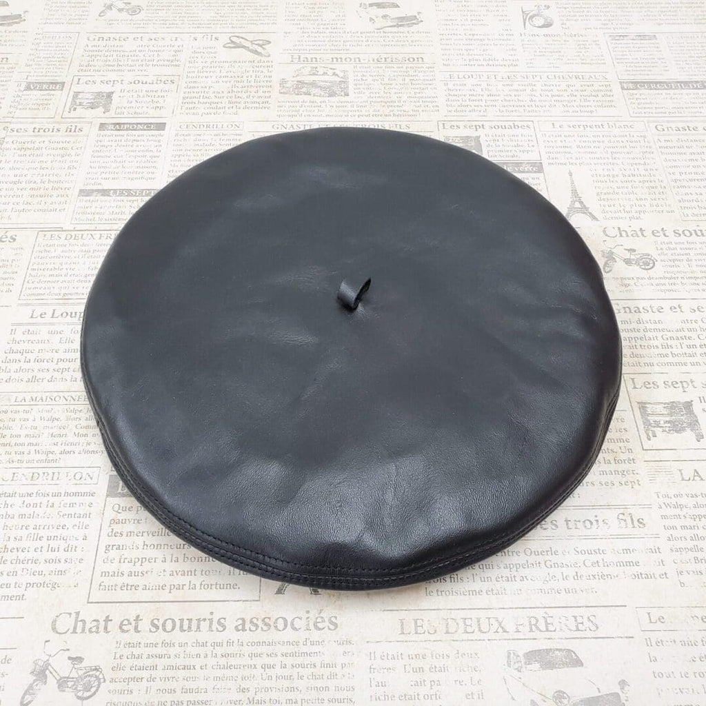 A black leather hat on top of newspaper.