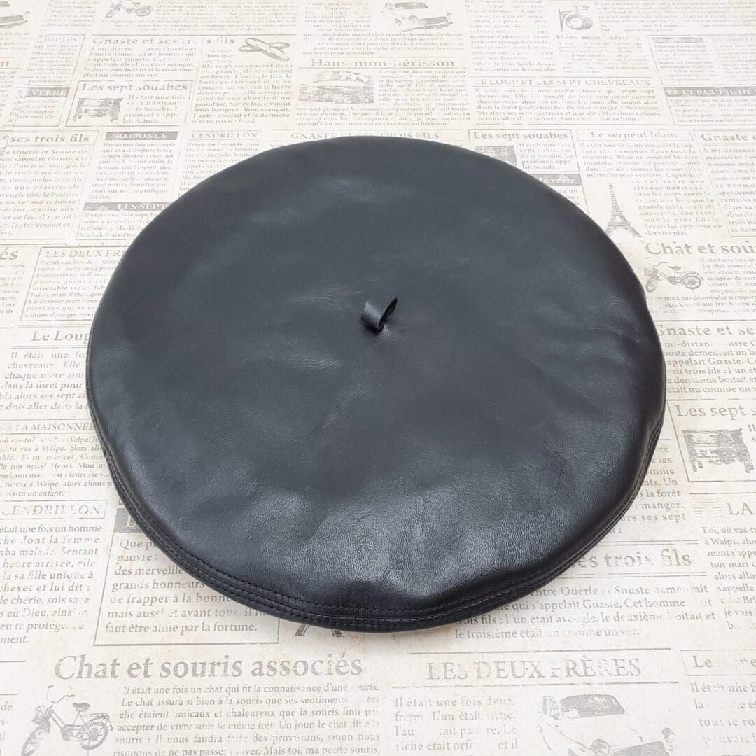 A black leather hat on top of newspaper.