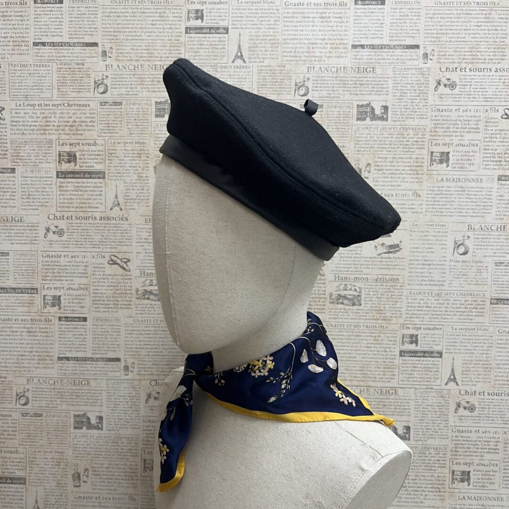 A mannequin wearing a black beret and scarf.