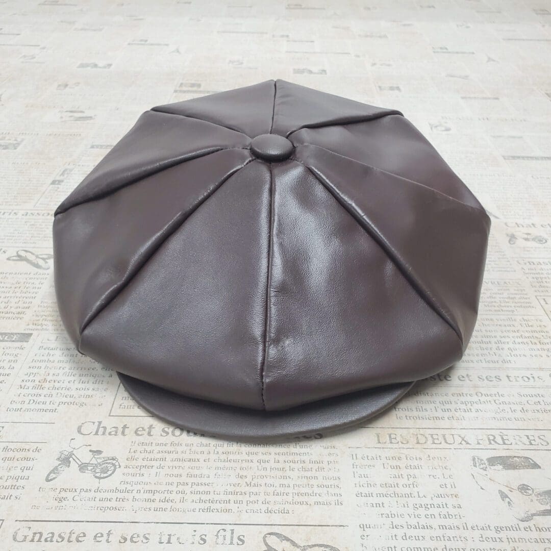 A brown leather hat sitting on top of a newspaper.