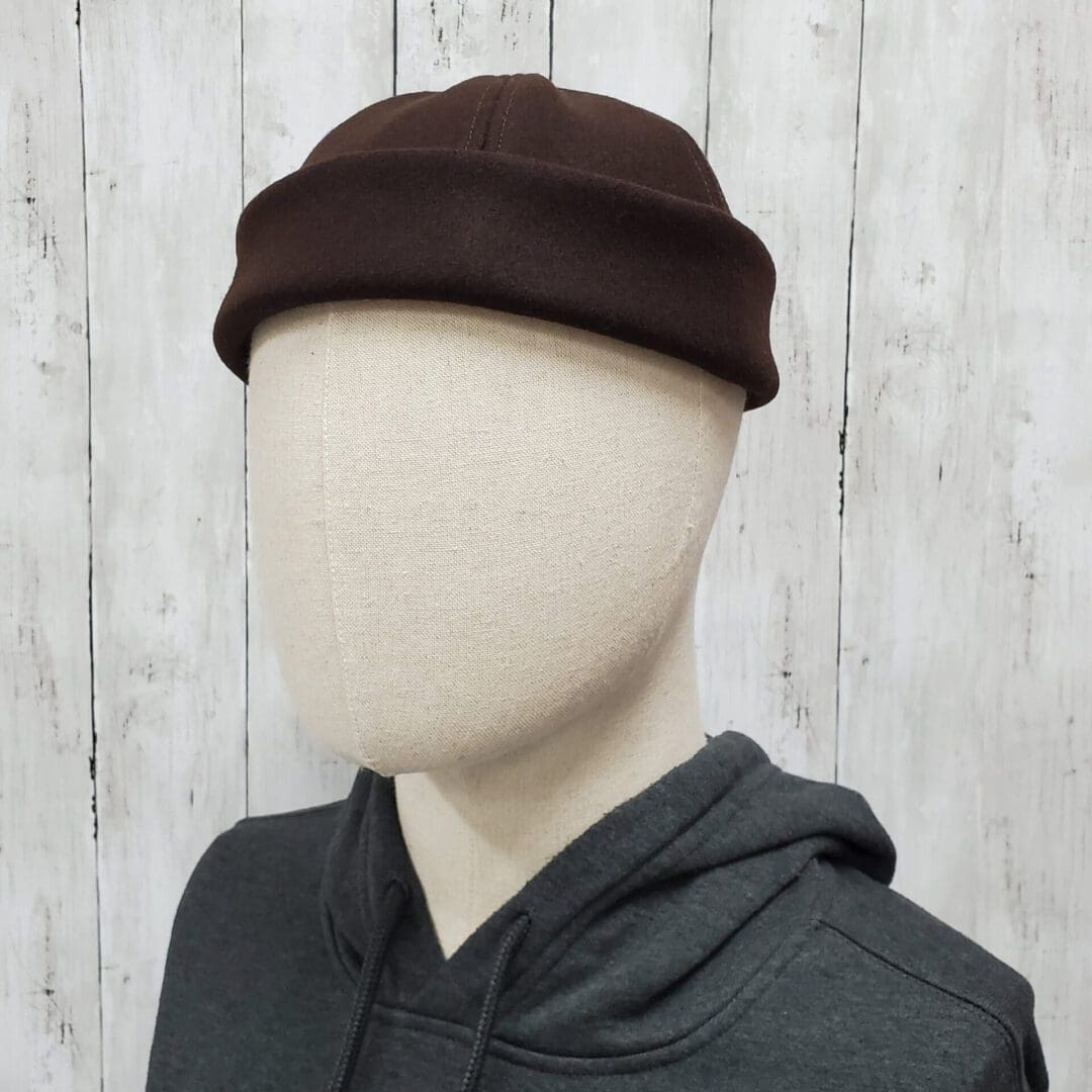 A person wearing a hat with a wooden background