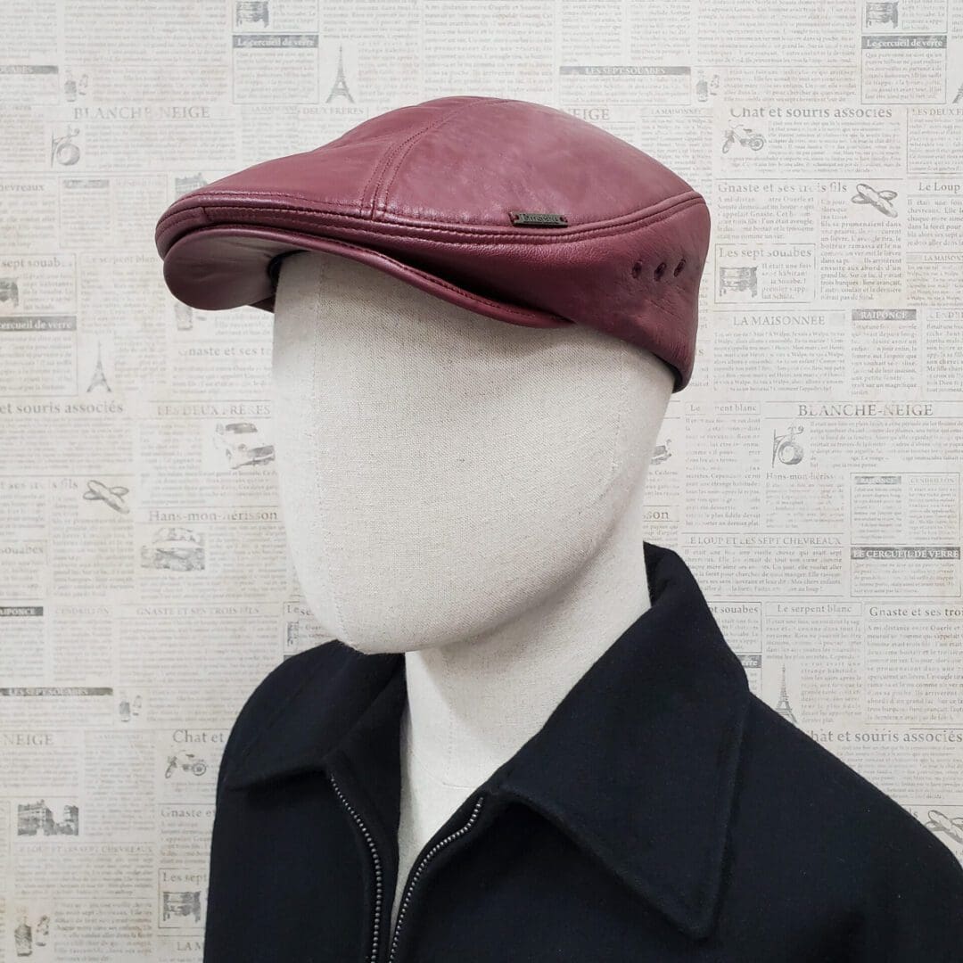 A man wearing a hat and jacket in front of a wall.