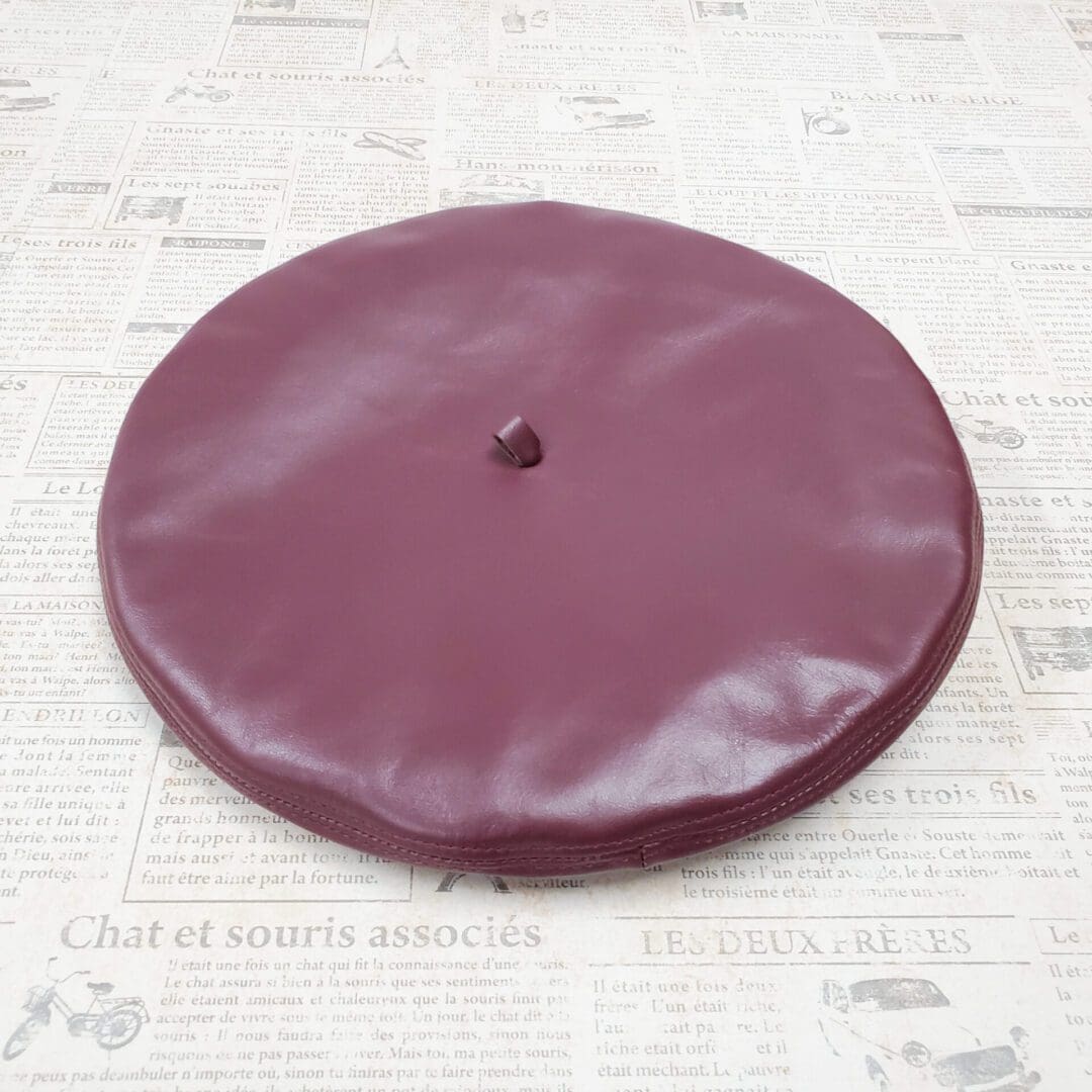 A purple leather hat on top of a table.