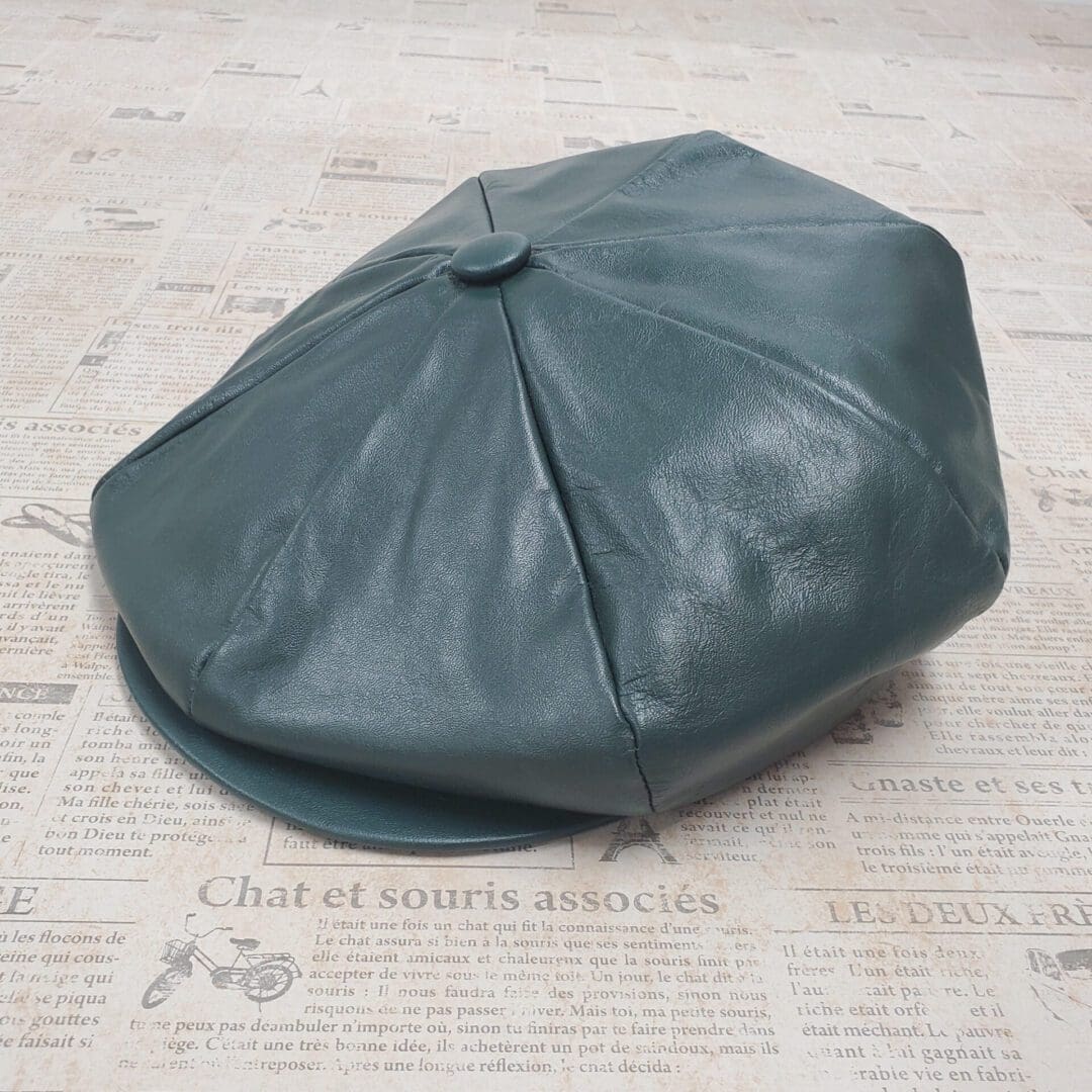 A green leather hat sitting on top of a newspaper.