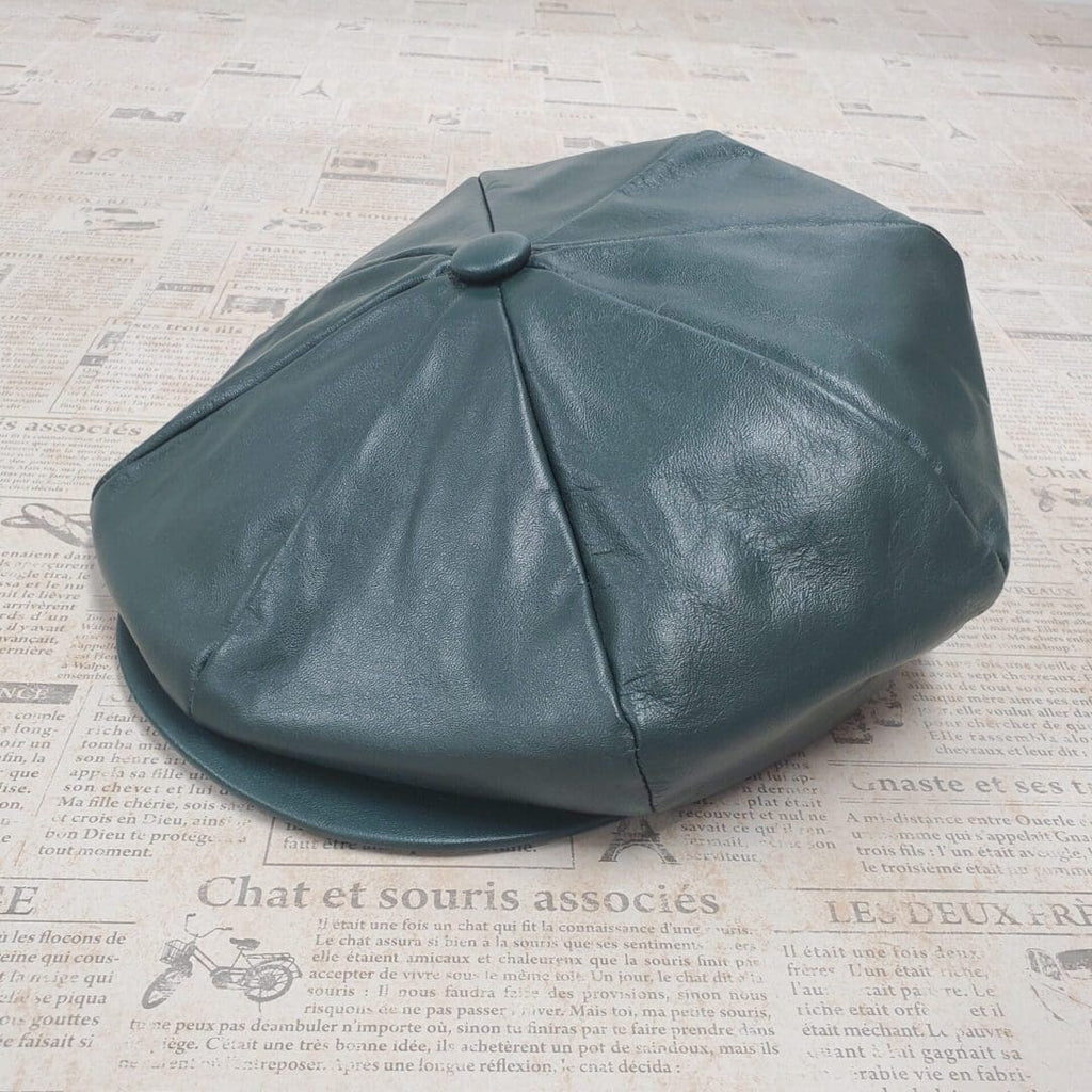 A green leather hat sitting on top of a newspaper.