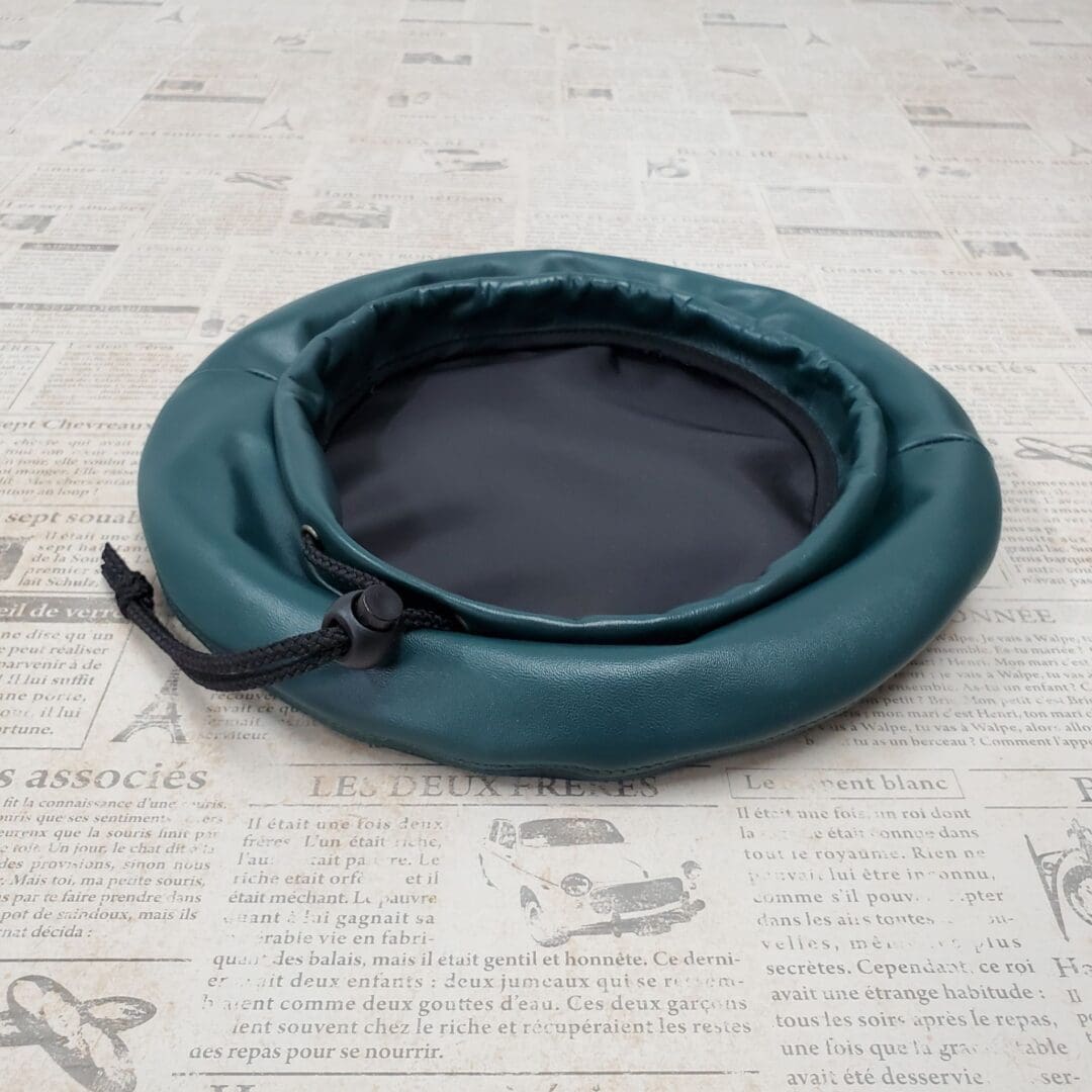 A green round bag sitting on top of a paper.