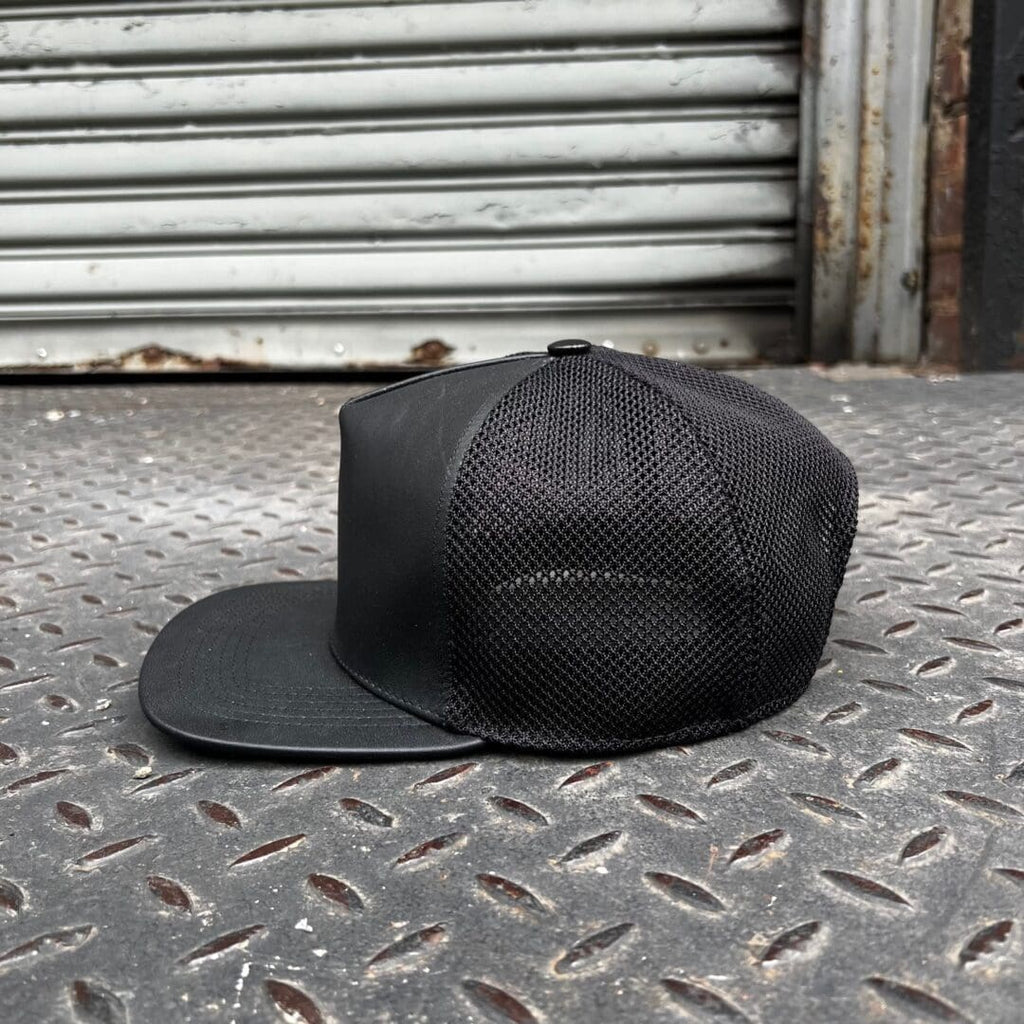 A black hat sitting on the ground outside.