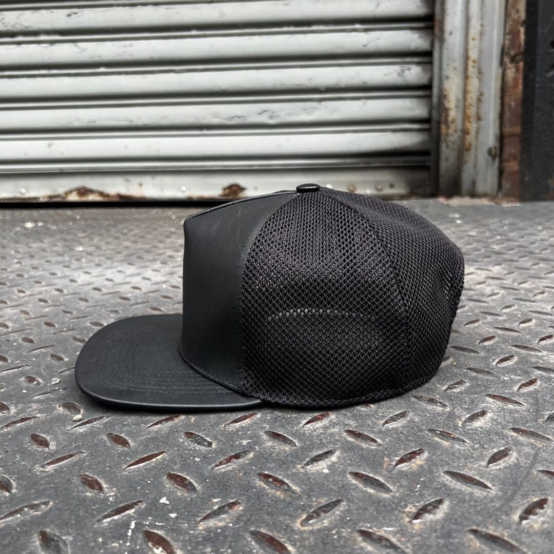 A black hat sitting on the ground outside.