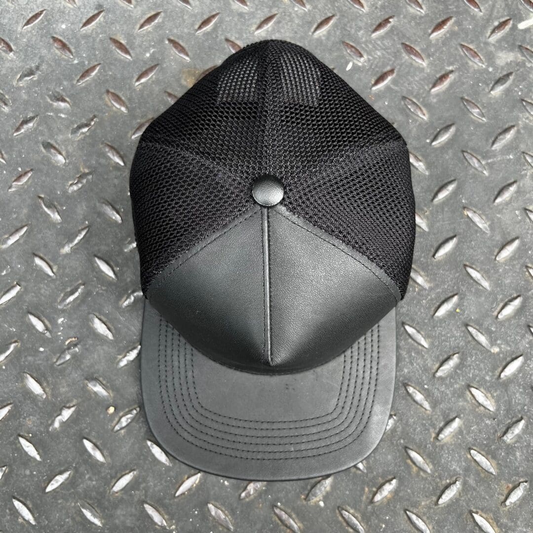 A black and gray hat sitting on top of a metal floor.