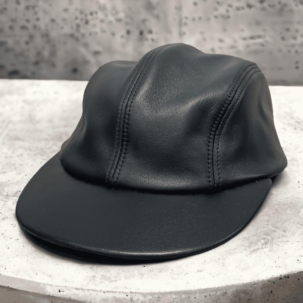 A black leather hat sitting on top of a concrete table.