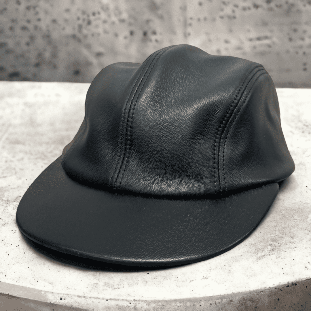 A black leather hat sitting on top of a concrete table.