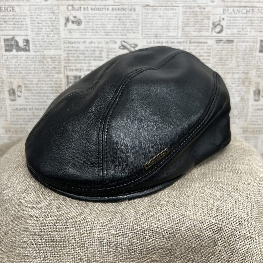A black leather hat sitting on top of a chair.