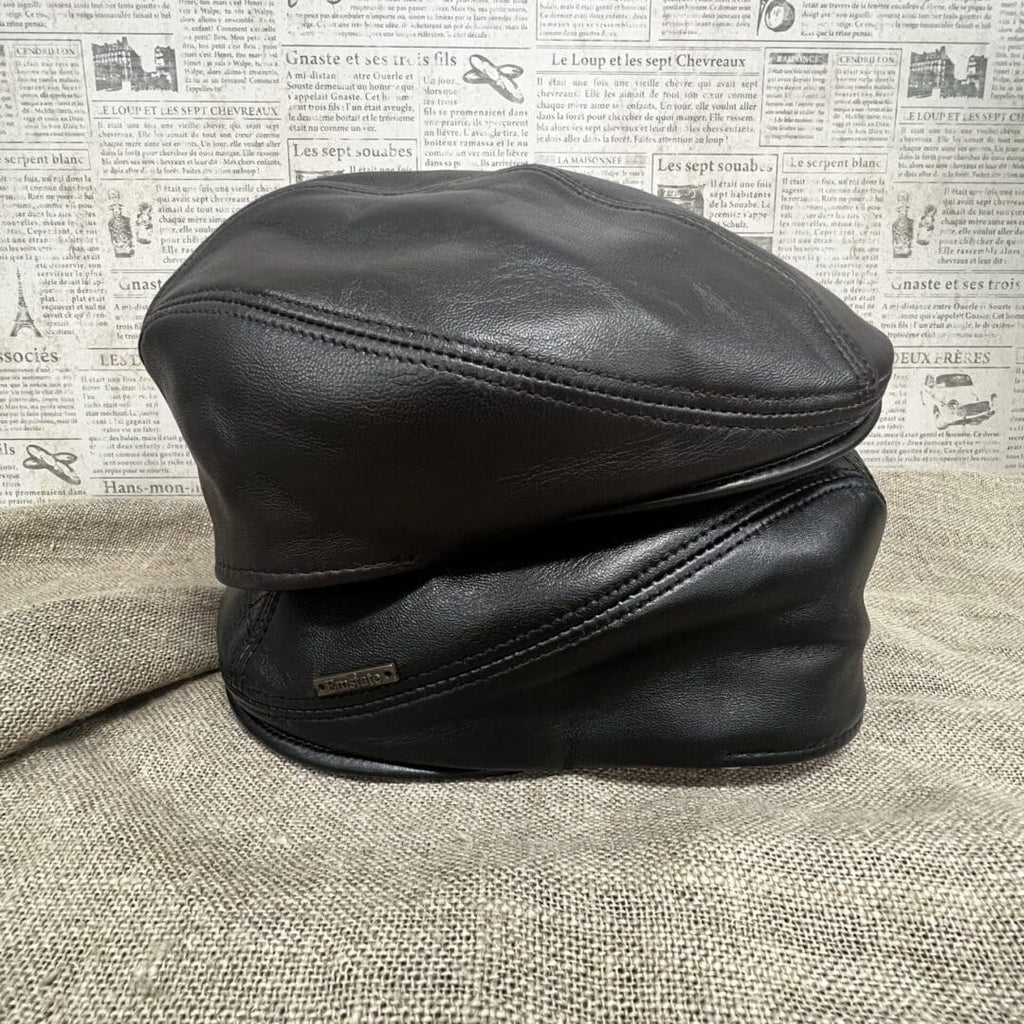 A pair of black leather hats sitting on top of each other.
