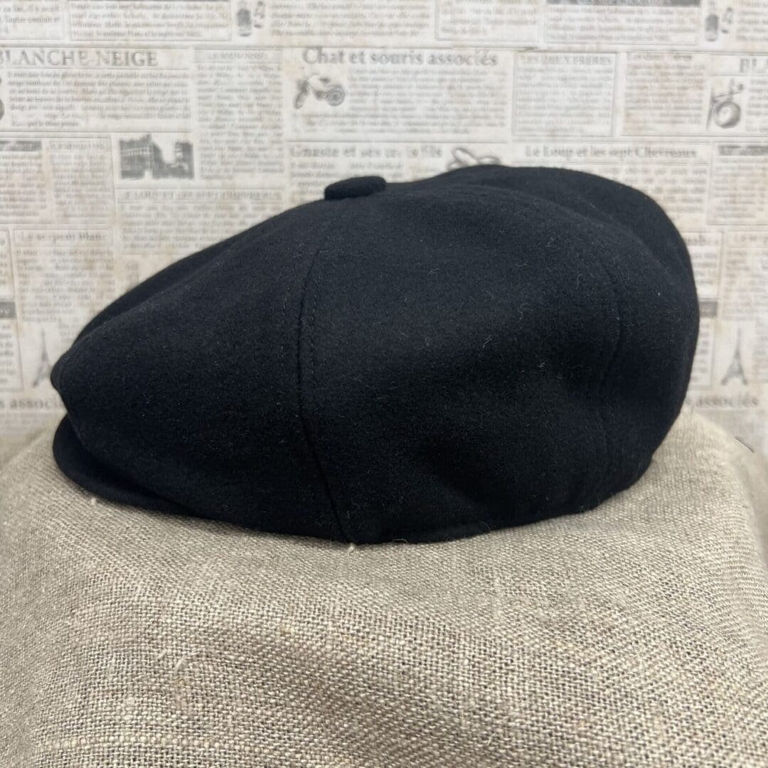 A black hat sitting on top of a brown blanket.