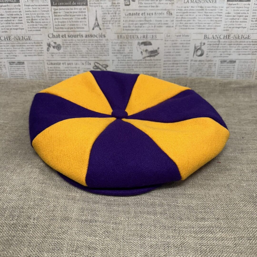 Purple and gold eight-panel newsboy cap.