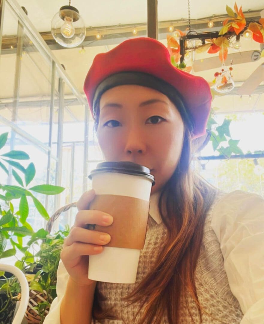 Woman in red beret drinking coffee.