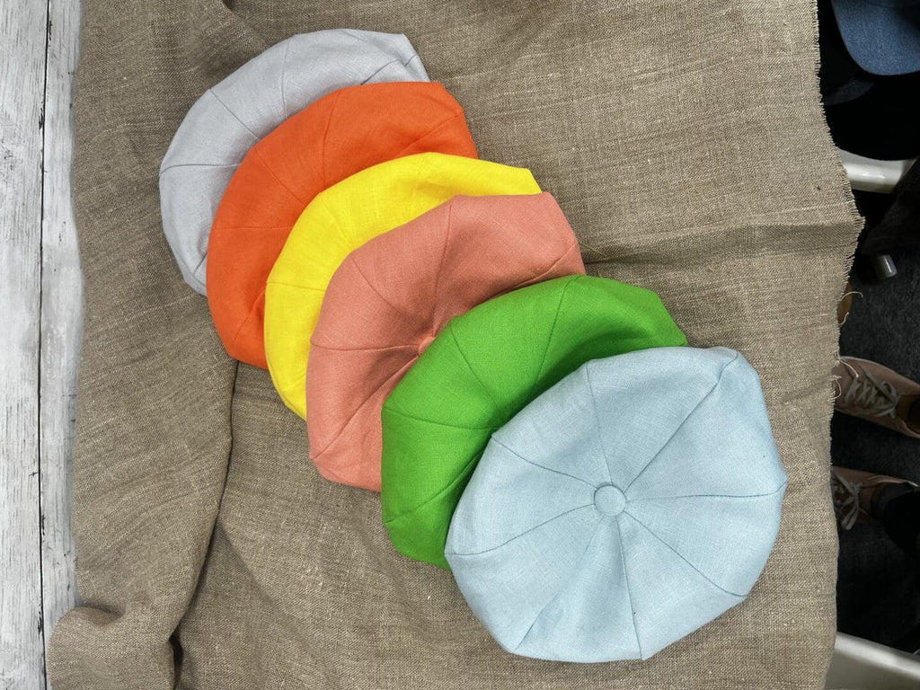 A group of six different colored hats on top of a blanket.