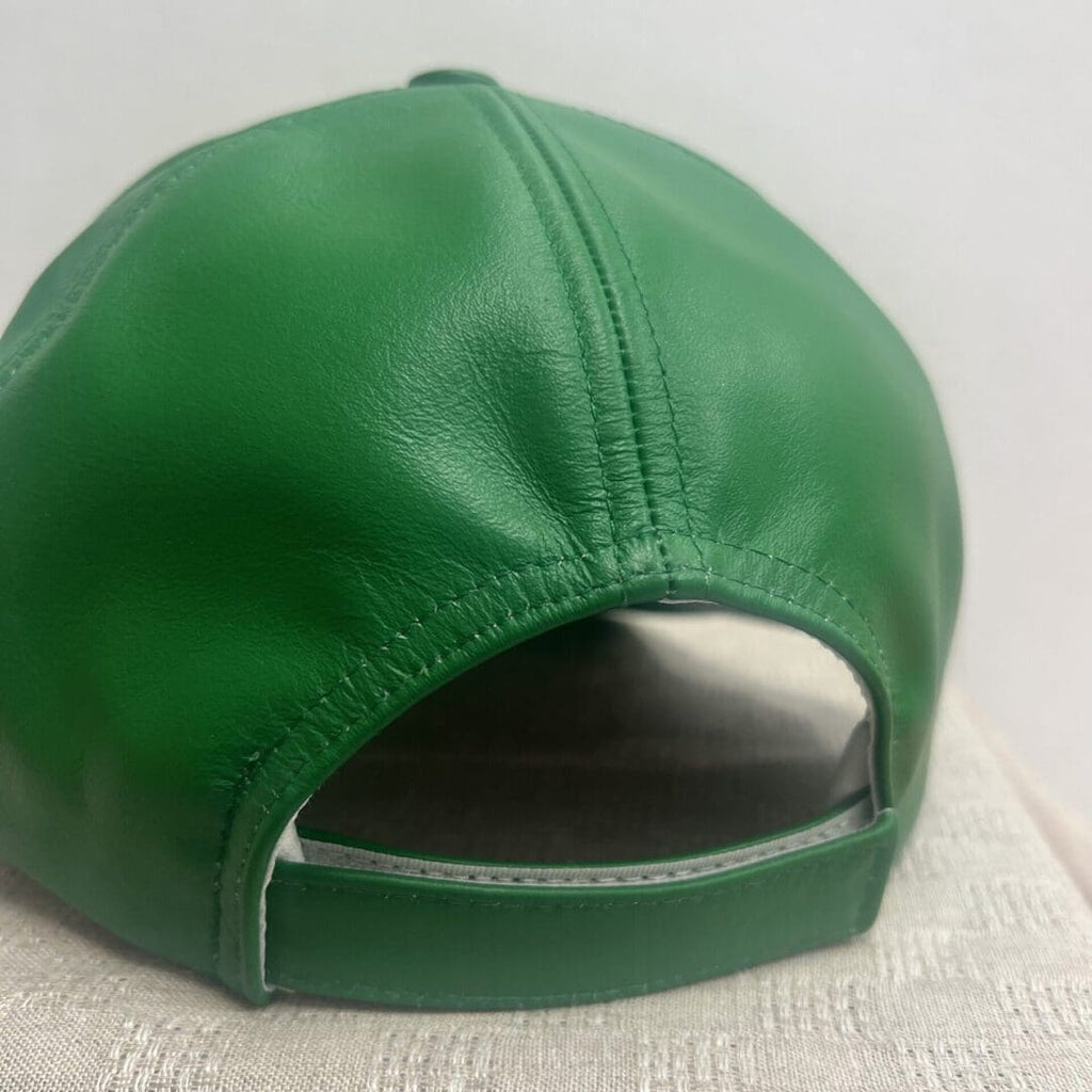 A green leather hat is shown on top of a white cloth.