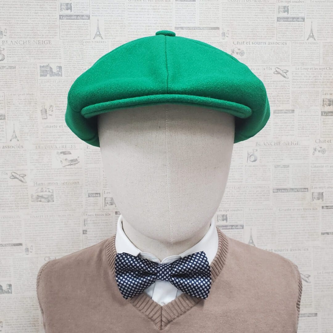 A mannequin wearing a green hat and bow tie.