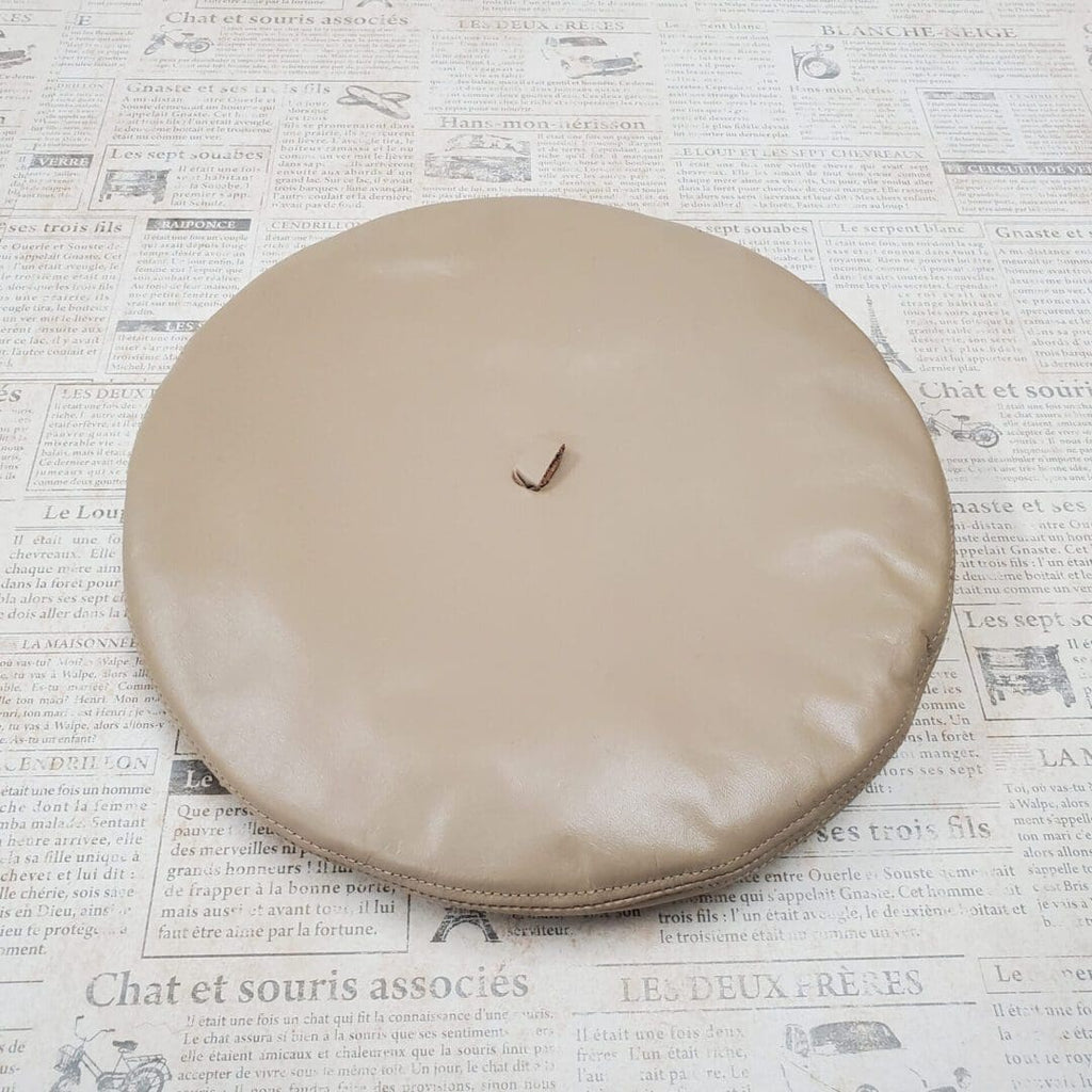A round tan pillow sitting on top of a table.