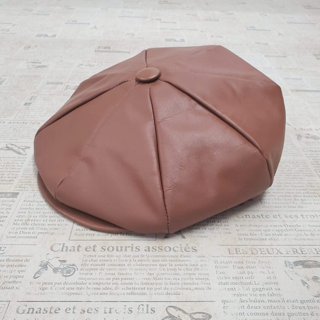 A brown hat sitting on top of a newspaper.