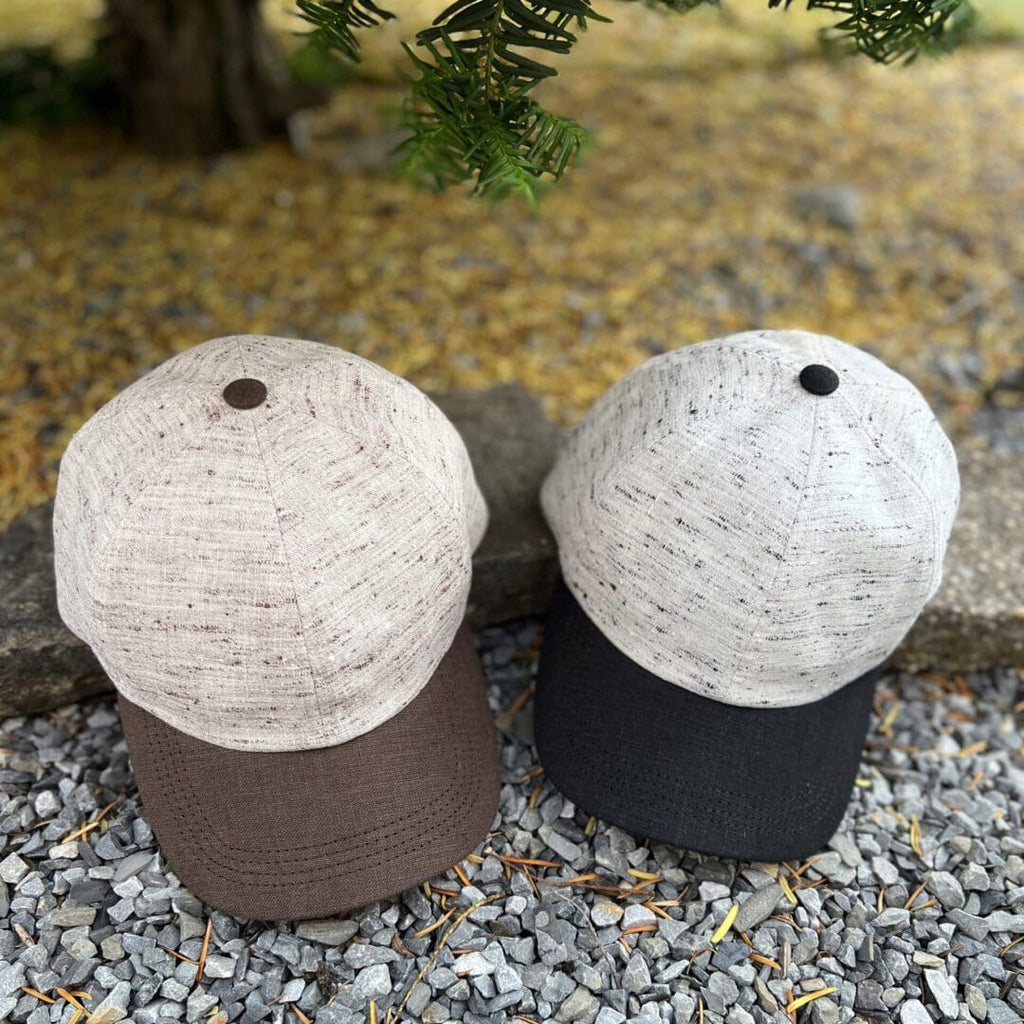 Two hats are sitting on the ground near a tree.