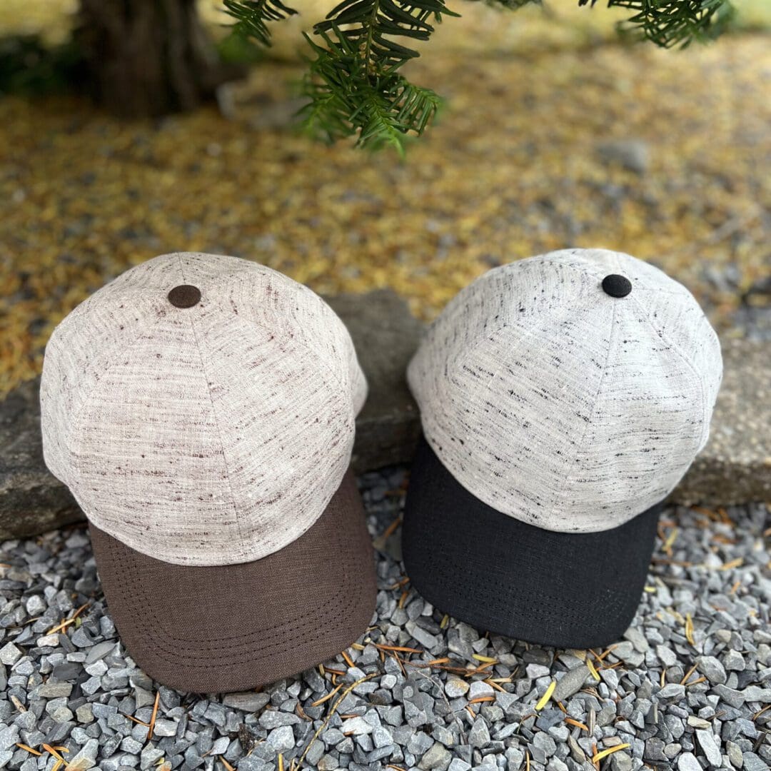 Two hats are sitting on the ground near a tree.