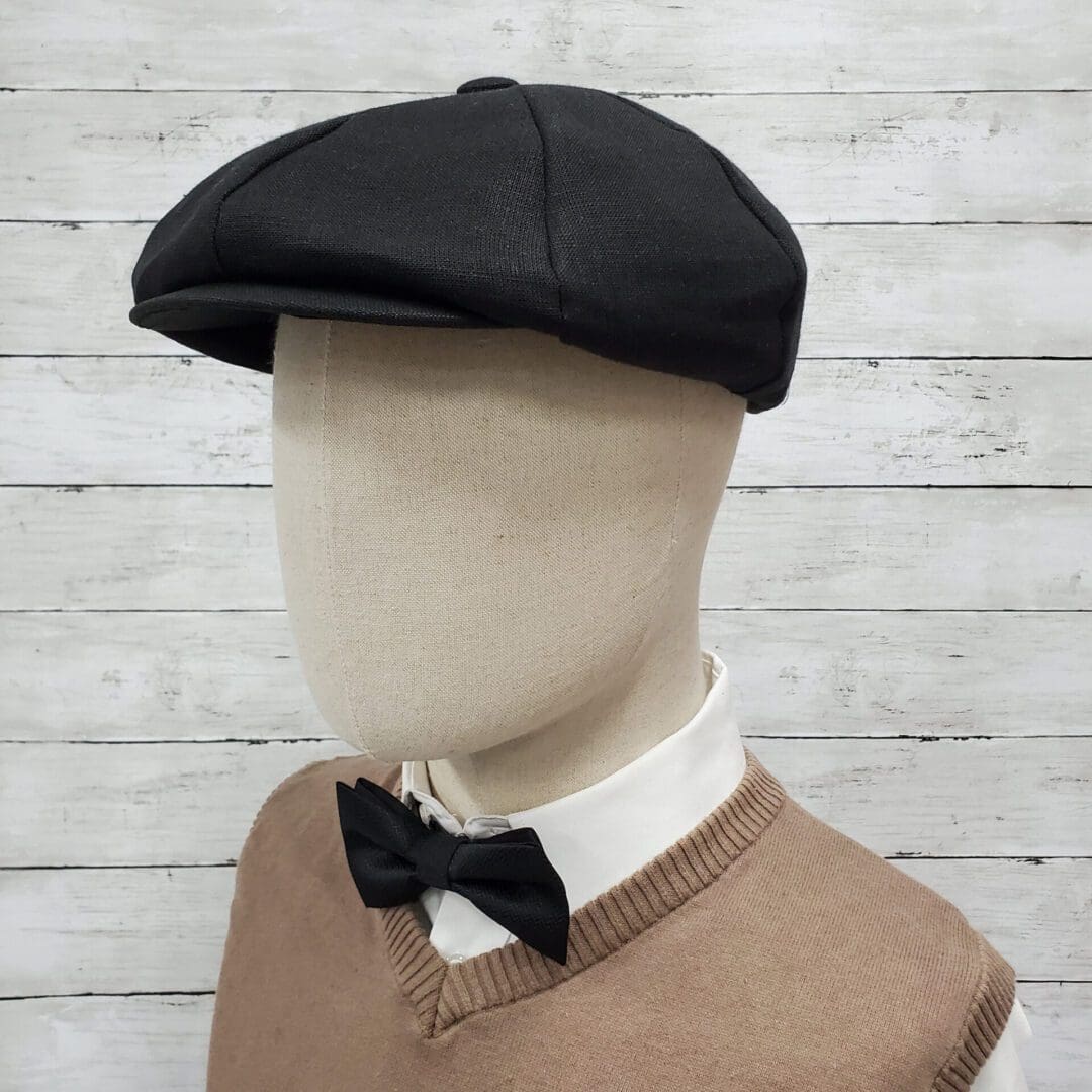 A mannequin wearing a black hat and bow tie.