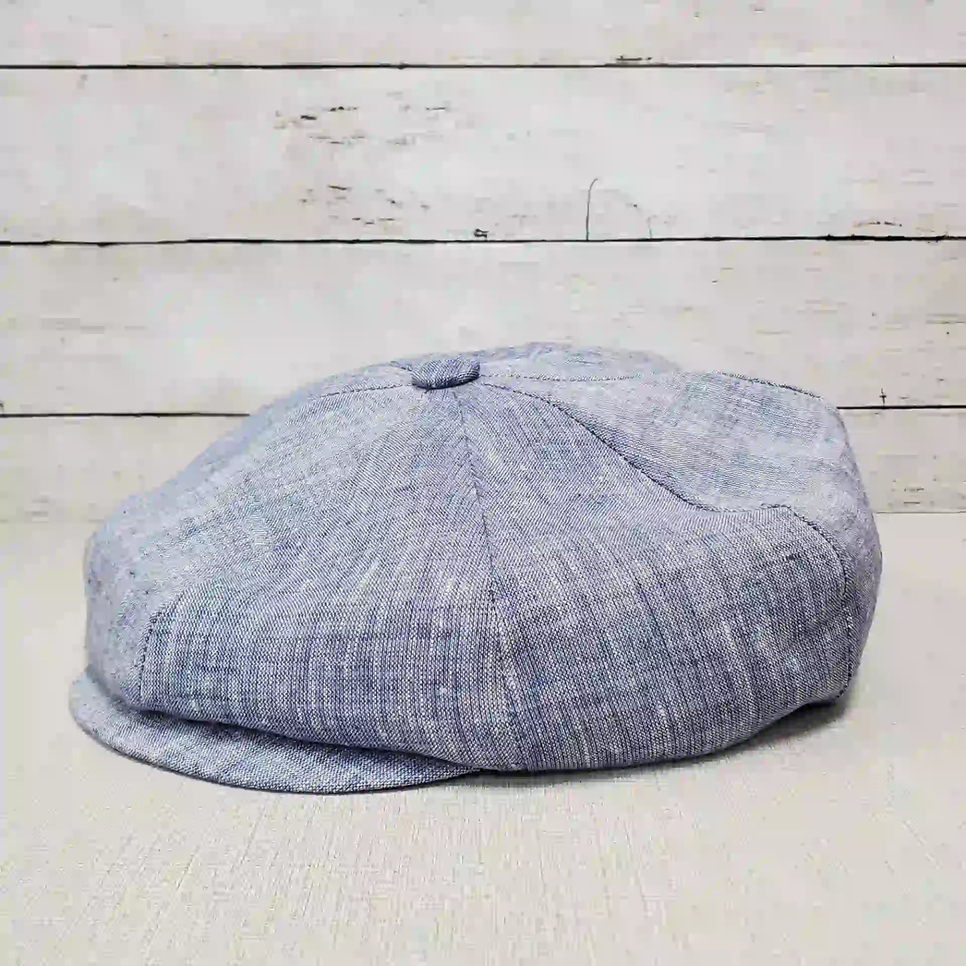 Gray flat cap on wooden background.