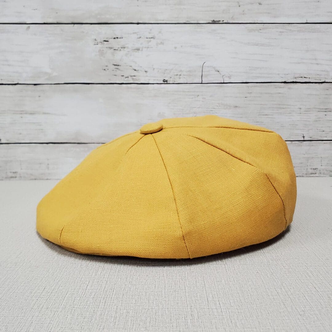 A yellow hat sitting on top of a wooden table.