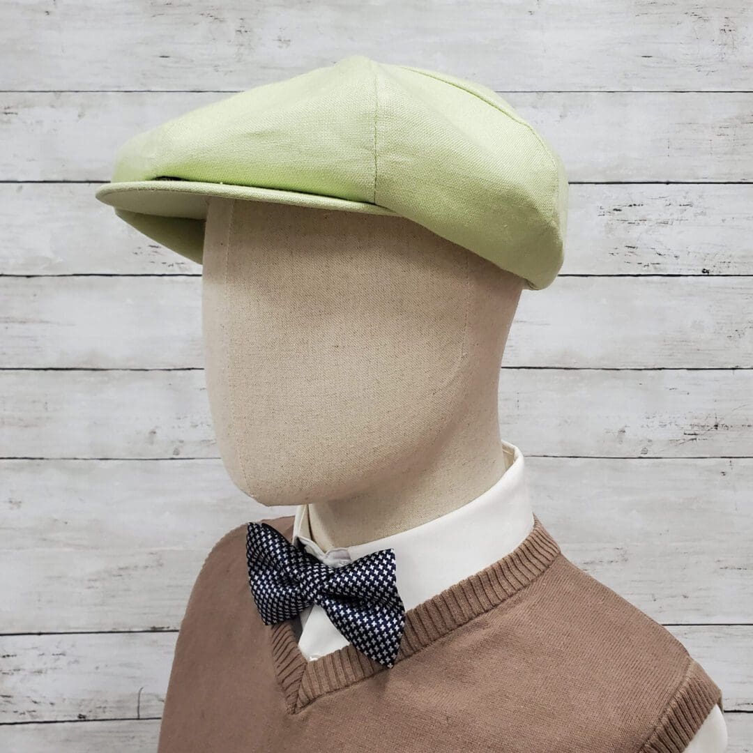 A mannequin wearing a green hat and bow tie.