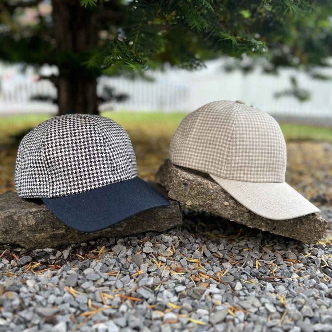Two hats are sitting on the ground near a tree.