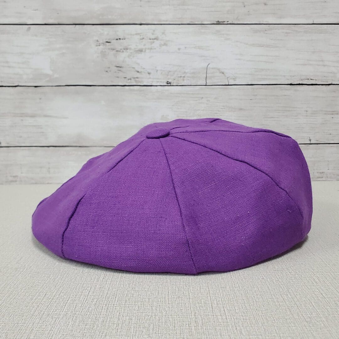 A purple hat sitting on top of a wooden table.