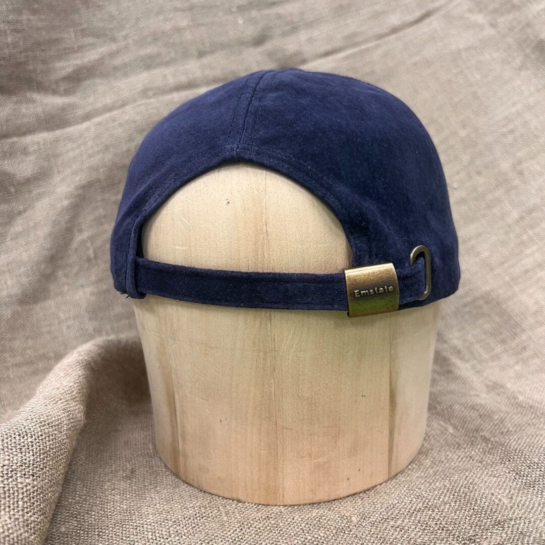 A wooden hat holder with a blue cap on top of it.