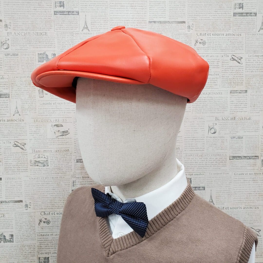 A mannequin wearing an orange hat and bow tie.