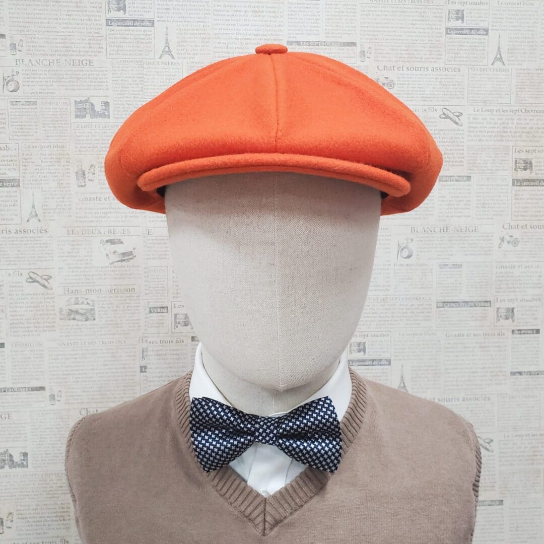 A mannequin wearing an orange hat and bow tie.