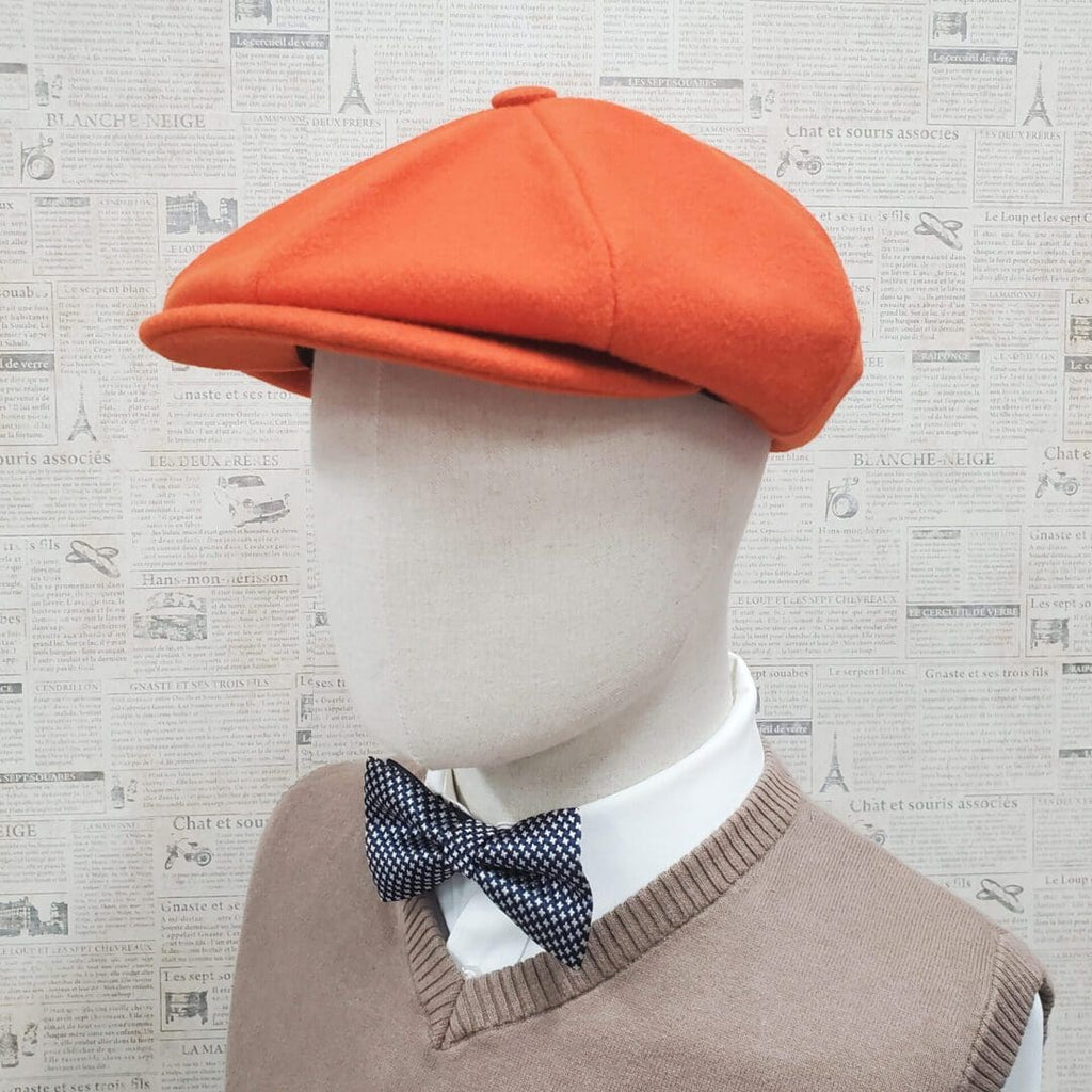 A mannequin wearing an orange hat and bow tie.