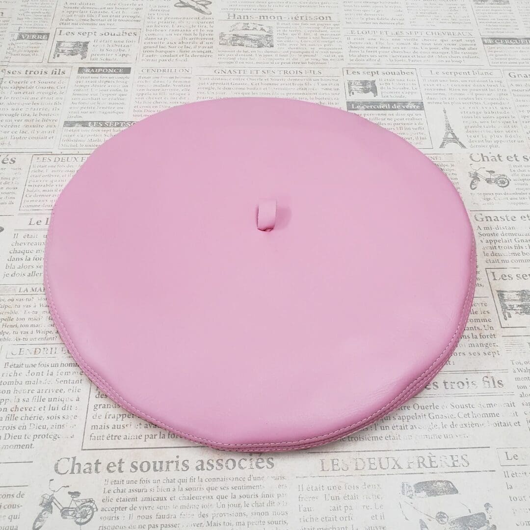 A pink frisbee sitting on top of a newspaper.