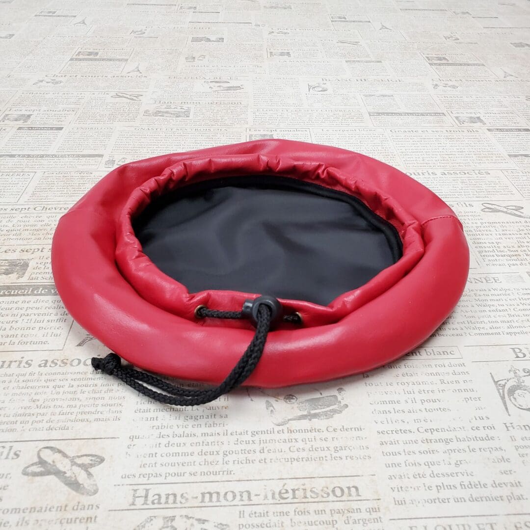 A red round bed with black top on the floor.