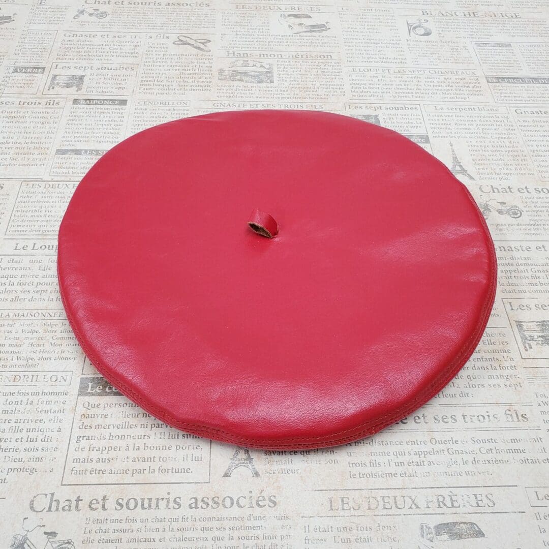 A red frisbee sitting on top of newspaper.