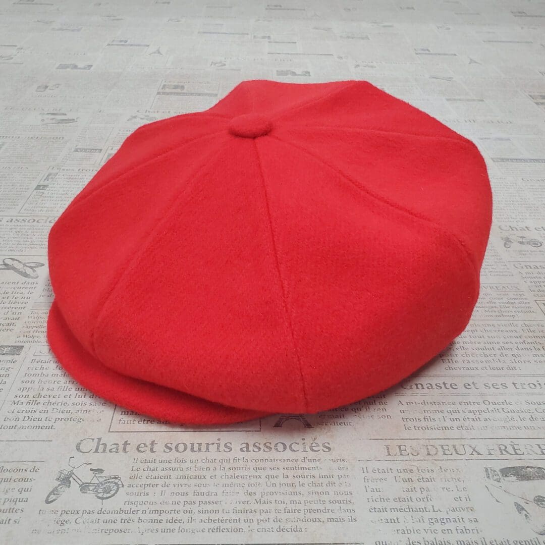 A red hat sitting on top of a newspaper.