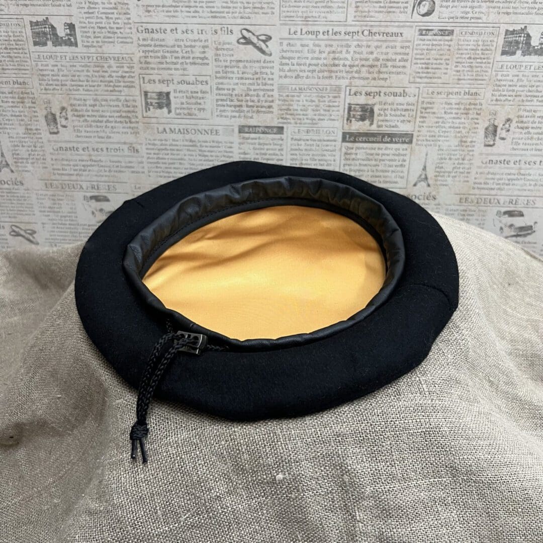 A black hat with yellow lining on top of a blanket.