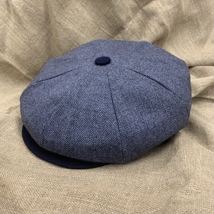 A blue hat sitting on top of a tan blanket.