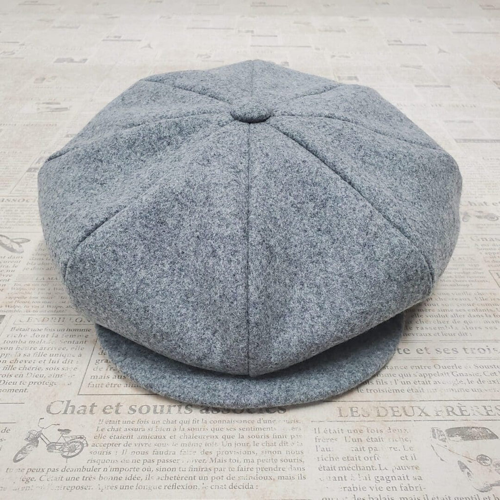 A gray hat sitting on top of a newspaper.
