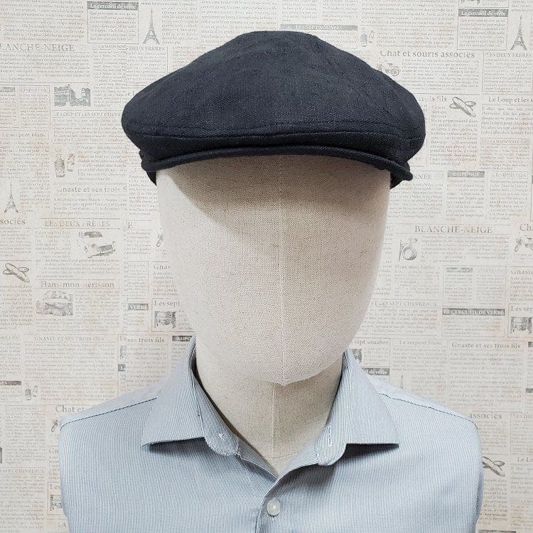 A man wearing a hat is standing in front of a wall.