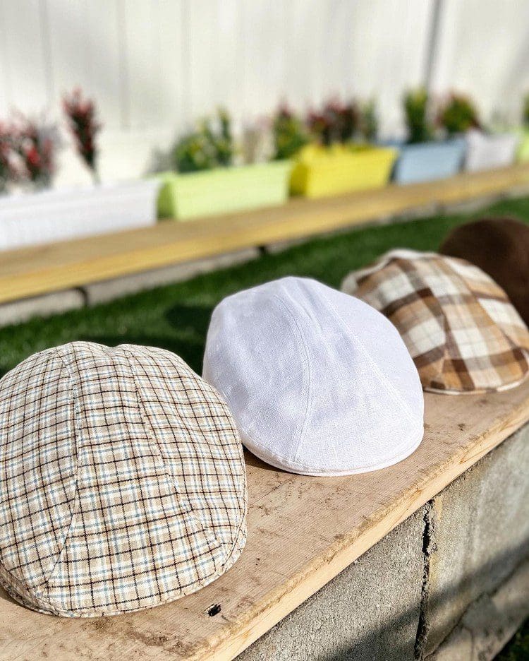 Three hats are sitting on a bench outside.