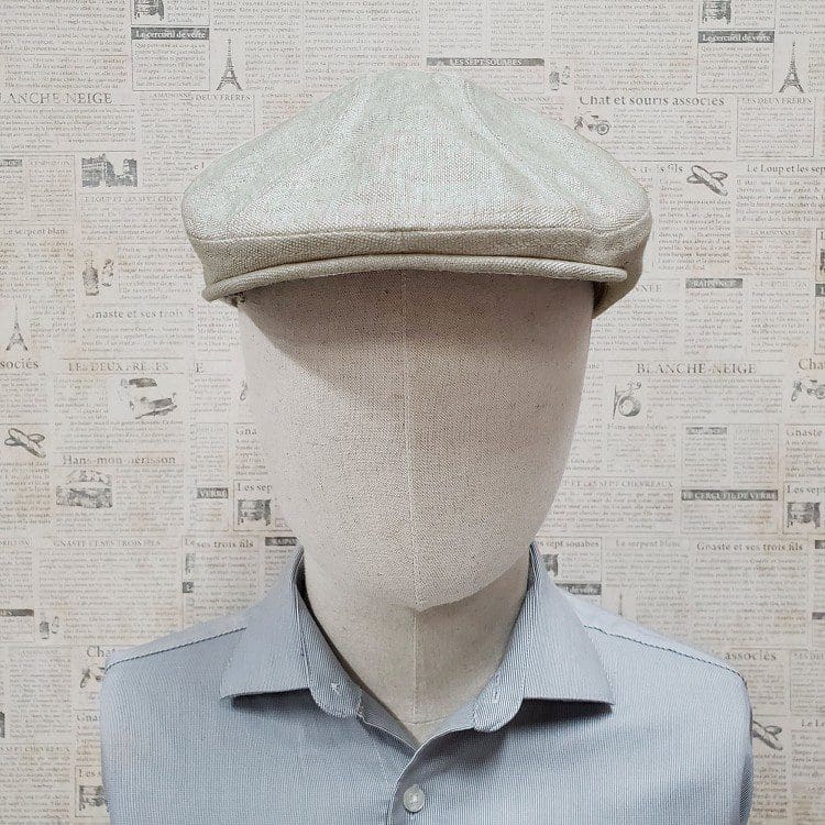 A mannequin wearing a hat in front of a wall.