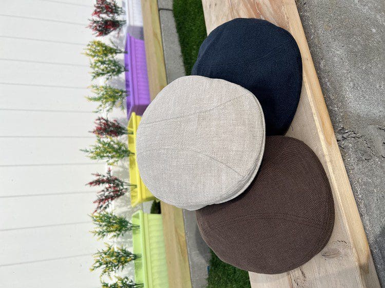 A group of three hats sitting on top of a wooden bench.